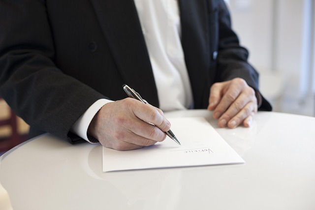 Person%20signing%20a%20contract%20at%20a%20round%20table Person signing a contract at a round table